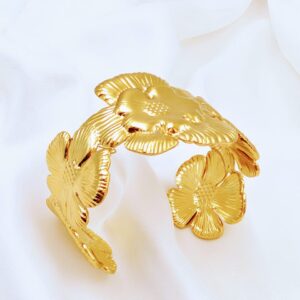 Golden flower cuff bracelet by Jhunkaar on a white satin background.