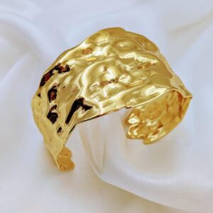Jhunkaar textured gold bracelet on a white silk background.